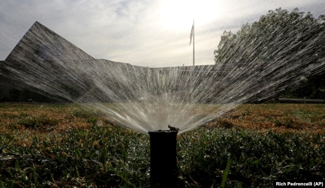FILE: Sprinklers water a grass lawn on July 15, 2014, in Sacramento, Calif.