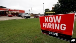 FILE- A bilingual help wanted sign for Auto Zone, a retailer of aftermarket automotive parts and accessories, is posted outside the store in Canton, Miss., Sept. 27, 2018.