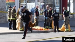 FILE - Firefighters stand near a covered body after a van struck multiple people at a major intersection northern Toronto, Ontario, April 23, 2018. The attacker was a self-identified incel — short for "involuntary celibate." 