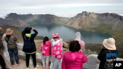 FILE - Chinese tourists take in the sight from a viewing platform overlooking the caldera of Mount Paektu near Samjiyon in North Korea, Aug. 18, 2018.