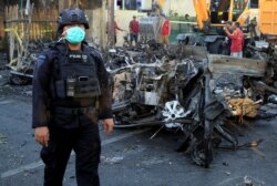 Seorang anggota Densus 88 berdiri di dekat bangkai mobil yang menabrak gereja di Gereja Pentakosta Surabaya Pusat (GPPS), Surabaya, 13 Mei 2018. (Foto: REUTERS/Beawiharta)