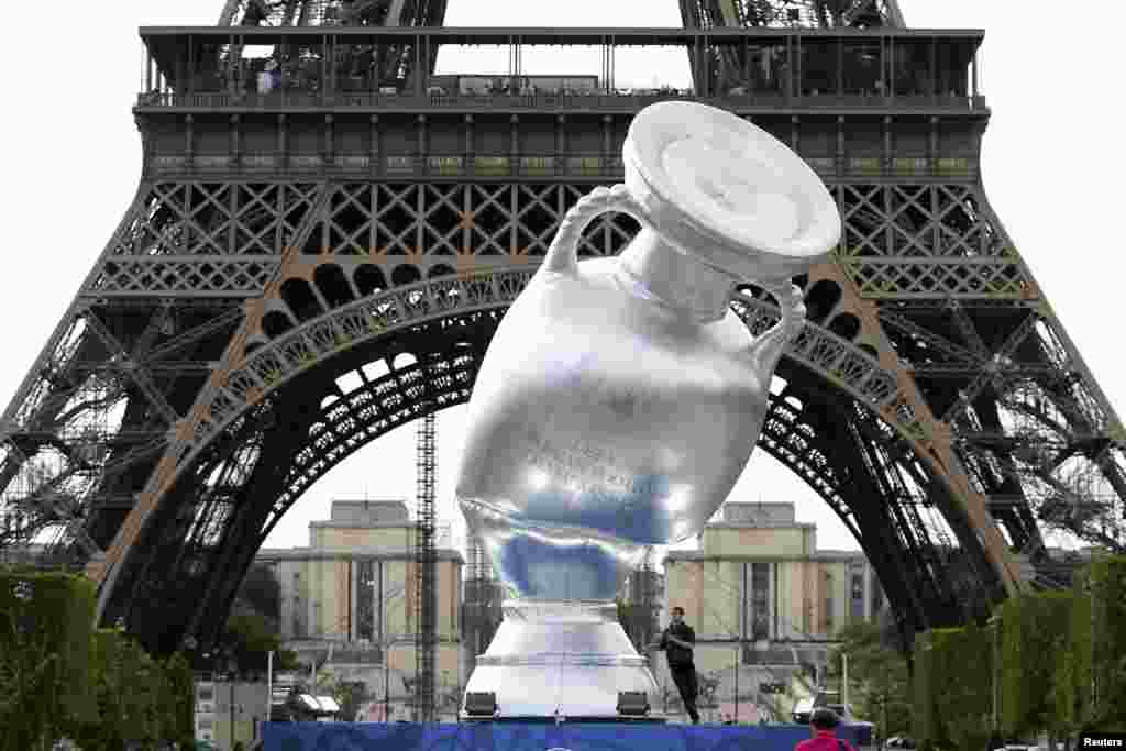 A workman deflates a 12-meter high replica of the Henri Delaunay Trophy near the Eiffel Tower in Paris, France, ahead of this week's brand and logo presentation of the UEFA EURO 2016.
