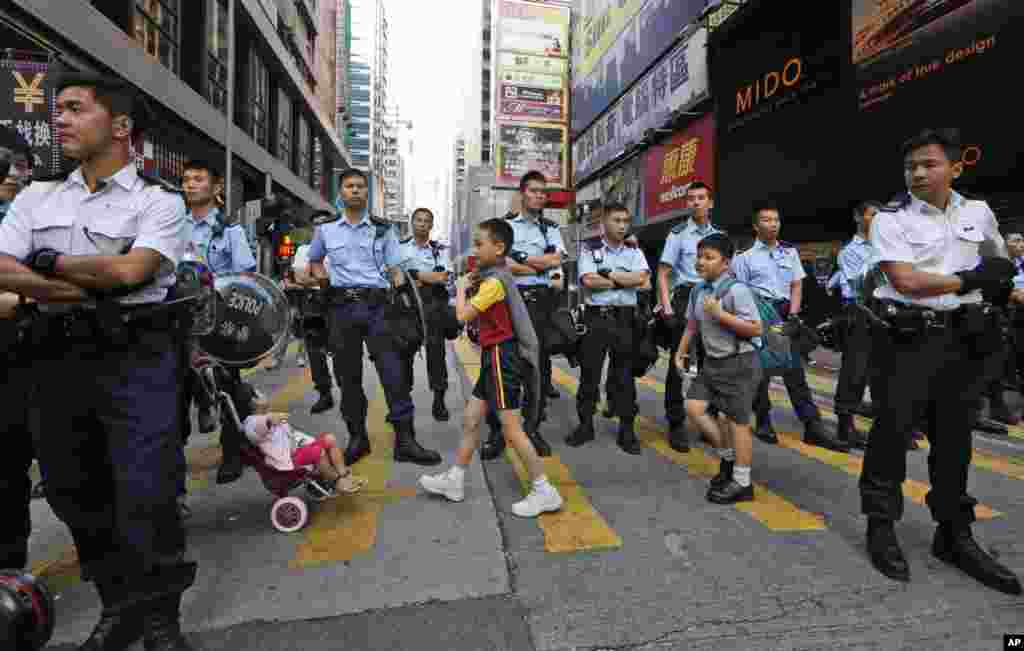 Students walk across the road on their way to school after police cleared the occupied area in the Mong Kok district of Hong Kong, Friday, Oct. 17, 2014.