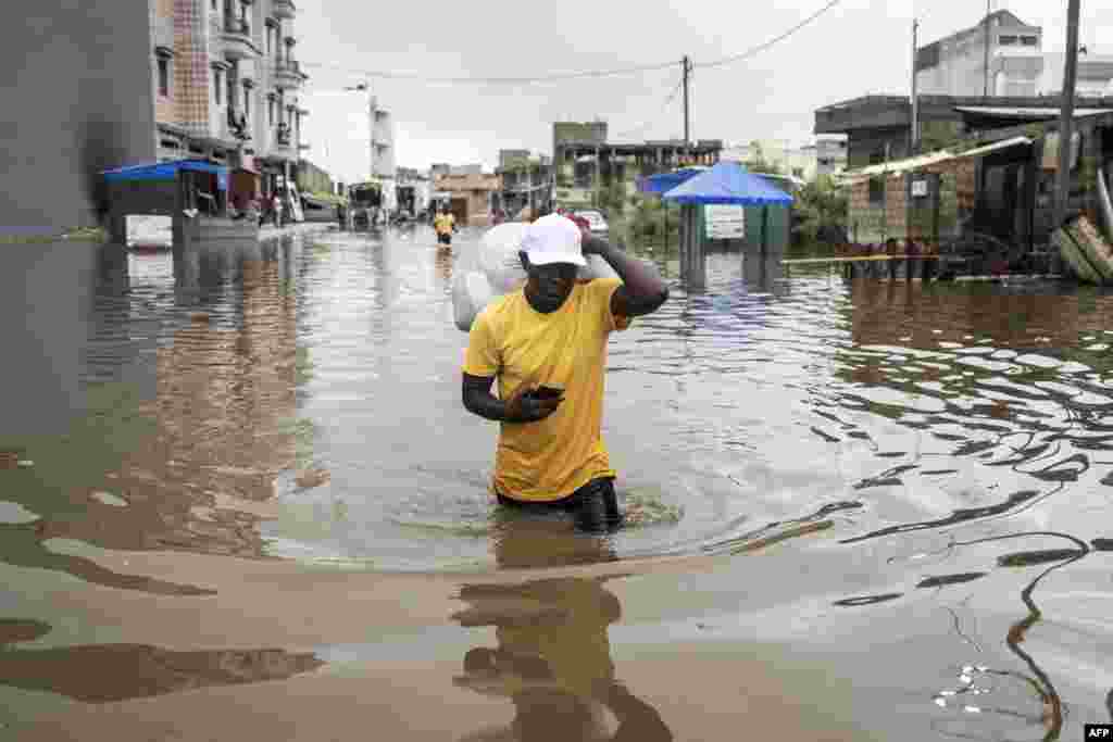 A man carries his belongings out of his house in the flooded neighborhood of Keur Massar, Dakar.