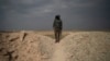 A U.S.-backed Syrian Democratic Forces (SDF) fighter stands atop a hill in the desert outside the village of Baghuz, Syria, Feb. 14, 2019. 