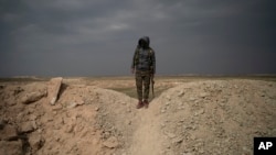2019年2月14日，一名美国支持的叙利亚民主力量战斗人员站在叙利亚村庄巴古兹村外的沙丘上。叙利亚民主力量在叙利亚东部两个村庄清除藏匿在当地人当中的伊斯兰国武装分子。（AP）
