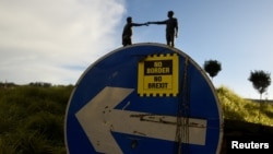 FILE - A "No Border, No Brexit" sticker is seen on a road sign in front of the Peace statue entitled "Hands Across the Divide" in Londonderry, Northern Ireland, Jan. 22, 2019.