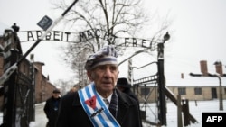 Auschwitz survivor Miroslaw Celka walks out the gate with the sign saying "Work makes you free" after paying tribute to fallen comrades at the "death wall" execution spot in the former Auschwitz concentration camp in Oswiecim, Poland, Jan. 27, 2014.