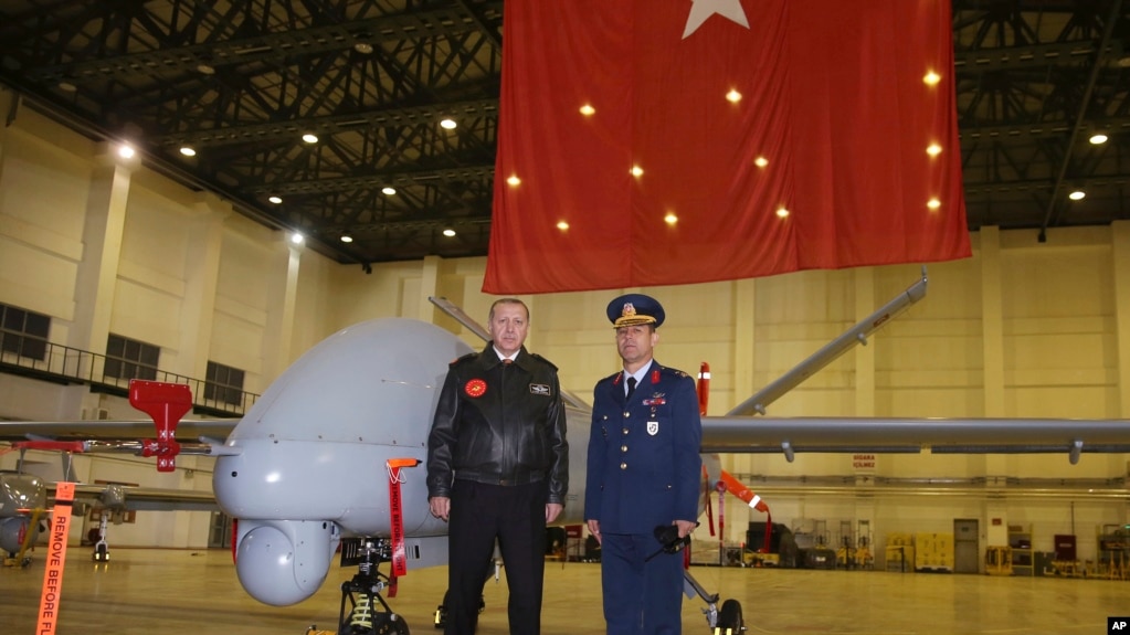 Turkey's President Recep Tayyip Erdogan poses for a photo with a Turkish army commander in front of a drone at a military airbase in Batman, Turkey, Saturday, Feb. 3, 2018.