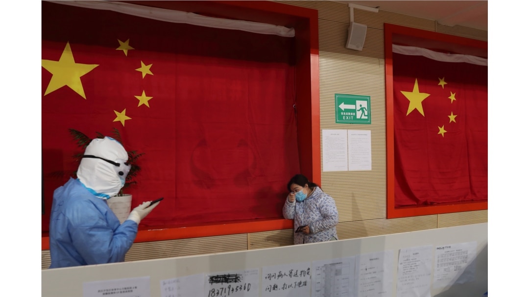 A medical worker in protective suit comforts a patient inside a sports stadium which has been converted into a makeshift hospital to treat patients of the novel coronavirus, in Wuhan, Hubei province, China February 27, 2020.