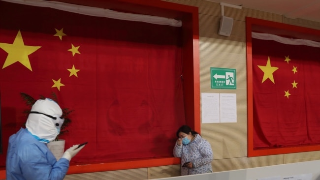 2020年2月27日，武汉一座体育馆改建的医院，一名医护人员试图安抚病患