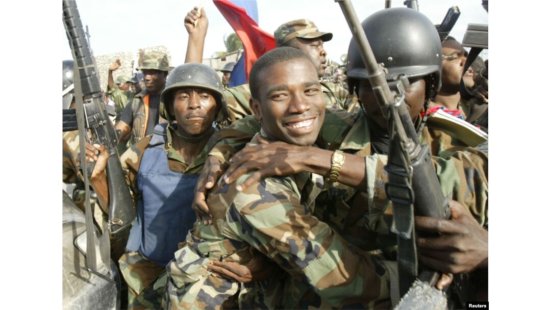 FILE - Haitian National Revolutionary Liberation Front Commander-in-Chief, Guy Philippe, hugs other soldiers, Feb. 22, 2004.