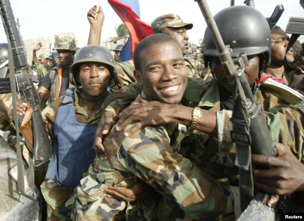 FILE - Haitian National Revolutionary Liberation Front Commander-in-Chief, Guy Philippe, hugs other soldiers, Feb. 22, 2004.