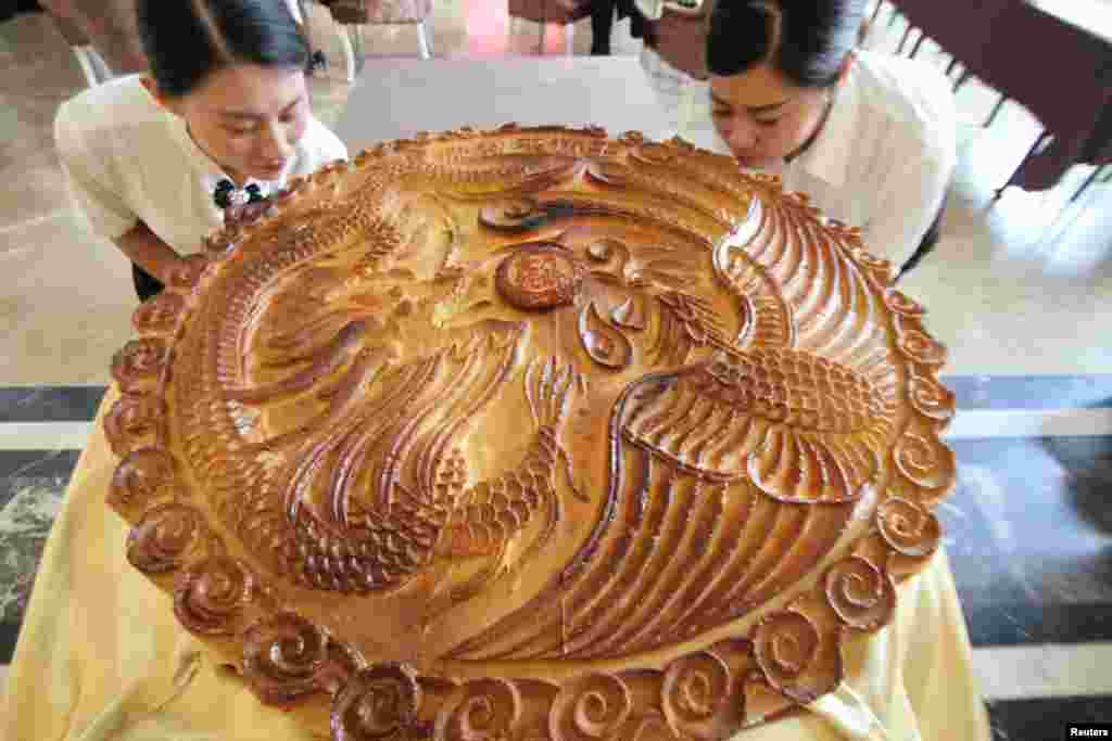 Staff pose with a giant moon cake ahead of China&#39;s Mid Autumn Festival in Binzhou, Shandong Province, China, Sept. 10, 2016.
