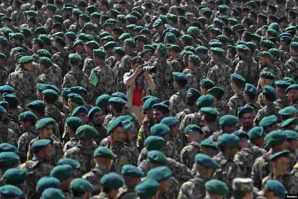 A photographer (C) takes pictures as newly graduated Afghan National Army (ANA) soldiers attend their graduation ceremony at the Kabul Military Training Center in Kabul. 
