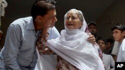 Abdul Aziz Sheikh, left, father of Sabika Sheikh, a victim of a shooting at a Texas high school, comforts an elderly woman at his home in Karachi, Pakistan, May 19, 2018.