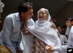 Abdul Aziz Sheikh, left, father of Sabika Sheikh, a victim of a shooting at a Texas high school, comforts an elderly woman at his home in Karachi, Pakistan, May 19, 2018.