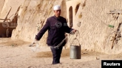 FILE - A villager in Tanshan, nestled among brown hills in central China's Ningxia region, walks to a well to fetch water Feb. 17, 2003.