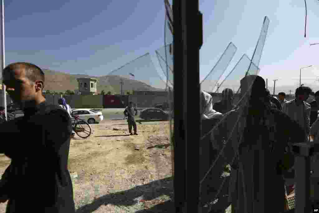 People look at a damaged shop after a suicide attack in the deputy counter-narcotic compound in Kabul, Afghanistan, July 22, 2014. 