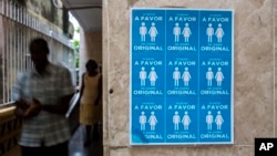 Cuban evangelists pass beside a poster in the Evangelist League Church that reads in Spanish, "I am in favor of the original design" in reference to discussions on same sex marriage to be included in new constitution in Havana, Cuba, Sunday, Oct. 7, 2018. (AP Photo/Desmond Boylan)