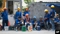 In this Monday Dec. 12, 2016 photo, Cambodian migrant construction workers wait for their transport home outside a building site in downtown Bangkok, Thailand.