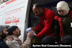 Syrian Red Crescent volunteers give medical supplies to civilians in Ghouta, Syria, March 5, 2018, in this picture obtained from social media.