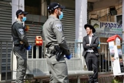 FILE - In this Thursday, April 2, 2020 file photo, Israeli border police officers question an Ultra orthodox man as part of the government's measures to help stop the spread of the coronavirus in the orthodox city of Bnei Brak, a Tel Aviv suburb, Israel.