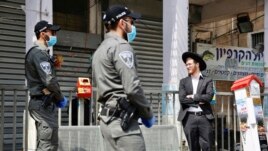 FILE - In this Thursday, April 2, 2020 file photo, Israeli border police officers question an Ultra orthodox man as part of the government's measures to help stop the spread of the coronavirus in the orthodox city of Bnei Brak, a Tel Aviv suburb, Israel.