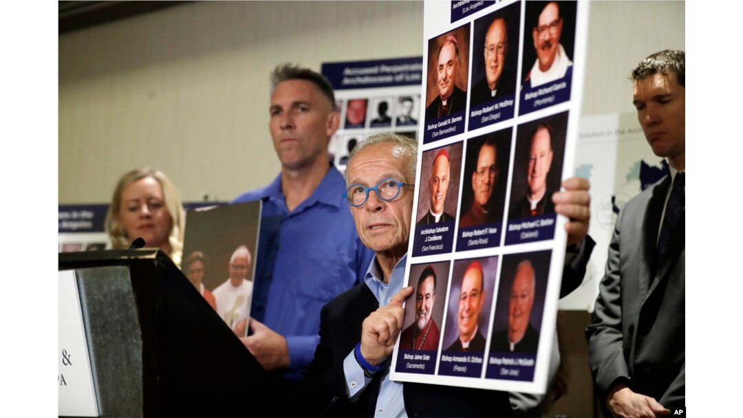 Attorney Jeff Anderson, center, holds photographs of clergy accused of sexual abuse, next to abuse survivor Tom Emens, second from left, Oct. 2, 2018, in Los Angeles.