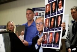 Attorney Jeff Anderson, center, holds photographs of clergy accused of sexual abuse, next to abuse survivor Tom Emens, second from left, Oct. 2, 2018, in Los Angeles.