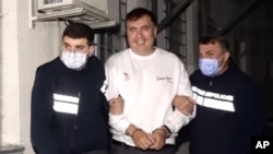 In this handout photo taken from video released by Georgian Interior Ministry Press Service, Georgian Police officers escort former President Mikheil Saakashvili after he was arrested in Rustavi, Georgia, Friday, Oct. 1, 2021. The prime minister of Georgi