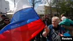 A woman shouts and waves a Russian flag during the celebrations for the 70th anniversary of the liberation of Simferopol from fascist troops during the World War Two outside of the village of Kurtsy near Simferopol in Crimea April 13, 2014. REUTERS/Maxim 