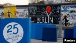 A sign, which reads "25 years Fall of the Wall 2014," is pictured in front of sections at the East Side Gallery, the largest remaining part of the former Berlin Wall in Berlin, Nov. 3, 2014. 