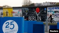 A sign, which reads "25 years Fall of the Wall 2014," is pictured in front of sections at the East Side Gallery, the largest remaining part of the former Berlin Wall in Berlin, Nov. 3, 2014. 