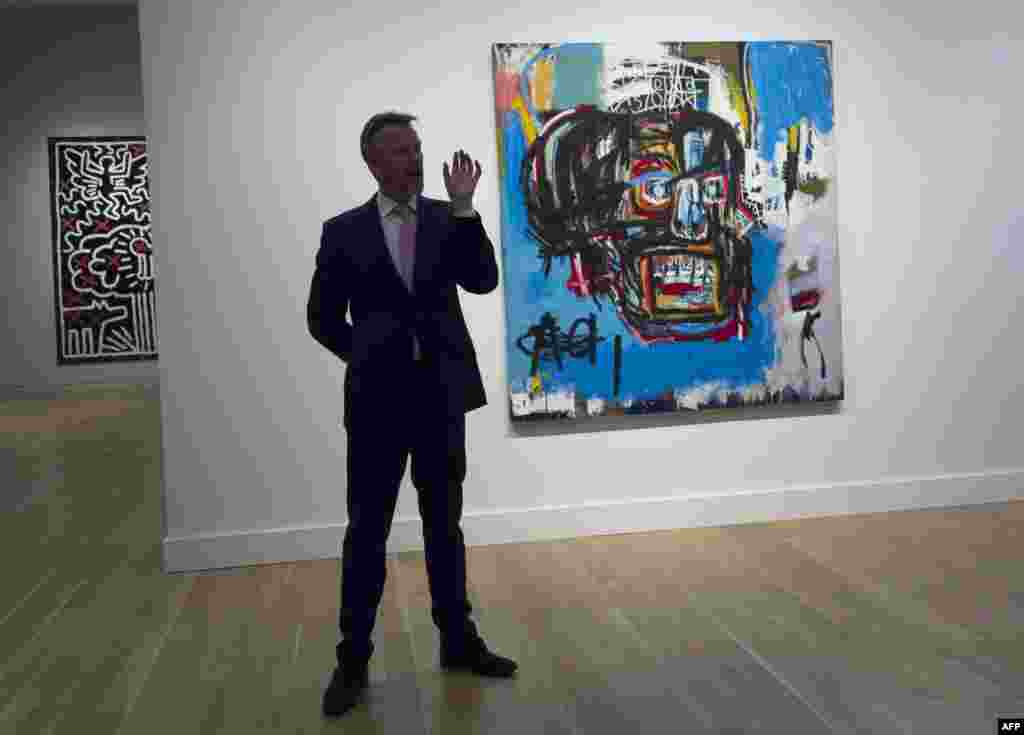 2017年5月18日，图片里的这幅油画卖了一亿1050万美元，创造了苏富比拍卖行的美国艺术家战后和现代艺术品的拍卖纪录。图为2017年5月5日在纽约苏富比拍卖行的媒体展示会上一位拍卖行官员谈论1982年巴斯奎特（Jean-Michel Basquiat，有人翻译成巴斯奇亚）创作的这幅油画《无题》（Untitled）。这幅画用油棒、丙烯酸和喷漆在巨型帆布上描绘了一个像是骷髅的人头。这幅画1984年的售价仅为19,000美元。另一幅巴斯奎特的作品，也叫《无题》，去年售价为5730万美元。巴斯奎特是黑人，出生在纽约，父亲是海地移民，母亲是波多黎各人。他在1988年因吸食海洛因过量而去世，年仅27岁。