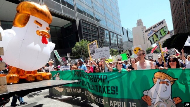 Un inflable gigante en forma de gallina, es llevado por los manifestantes que protestan contra el fracaso del presidente Donald Trump en publicar sus declaraciones en el centro de Los Ángeles el sábado 15 de abril de 2017.