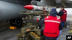 French Navy ordnance crew load a Mica missile under the wing of a Rafale fighter jet aboard France's flagship Charles de Gaulle aircraft carrier, March 25, 2011