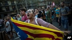 FILE - A woman carries an independence Catalan flag as demonstrators march downtown Barcelona, Spain, Tuesday Oct. 3, 2017. 