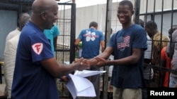 FILE - Cassius Kollie (R), 24, discharged from an Ebola treatment unit, receives a certificate for being cured of the disease in Paynesville, Liberia, July 20, 2015. 