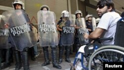 A protester in a wheelchair waits with other protesters for the troika inspectors from the European Commission, the International Monetary Fund and the European Central Bank to arrive for a meeting at the Labor ministry in Athens October 2, 2012. 