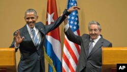 Cuban President Raul Castro, right, lifts up the arm of President Barack Obama at the conclusion of their joint news conference at the Palace of the Revolution, Monday, March 21, 2016, in Havana, Cuba. (AP Photo/Ramon Espinosa)