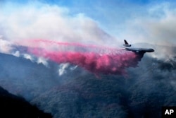 A firefighting DC-10 makes a fire retardant drop over a wildfire in the mountains near Malibu Canyon Road in Malibu, Calif., Nov. 11, 2018.