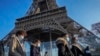 Orang-orang yang berjalan melewati Menara Eifel di Paris, Prancis, tampak mengenakan masker untuk mencegah perebakan COVID-19, pada 21 Desember 2021. Eropa telah mencatat lonjakan kasus baru COVID-19 sejak varian Omicron terdeteksi. (Foto: AP/Michel Euler)