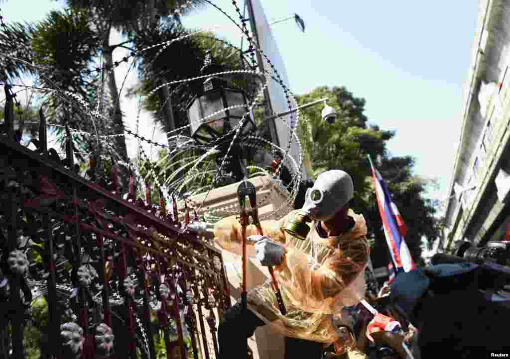 An anti-government protester uses a wire cutter in an attempt to break down the barriers at the Thai Police Headquarters, Bangkok, Thailand, Dec. 4, 2013.&nbsp;