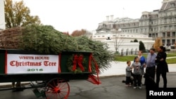 Ibu negara Michelle Obama dan dua keponakannya, Aaron dan Austin, menyambut datangnya pohon Natal di North Portico, Washington, 25 November 2016 (REUTERS/Gary Cameron )