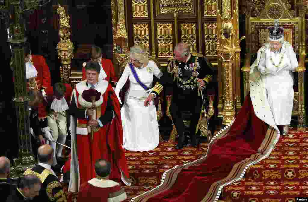 Thái tử Anh Charles (giữa) và bà Camilla, nữ công tước xứ Cornwall, phản ứng khi thấy một cậu bé giúp lễ ngất đi khi Nữ hoàng Anh Elizabeth đang đọc bài phát biểu tại Thượng Nghị viện trong buỗi lễ khai mạc Nghị viện tại Điện Westminster ở London.