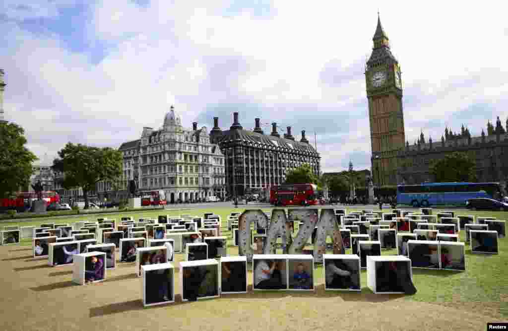 People sit in wooden boxes to represent living conditions in Gaza, during a protest, Parliament Square, London, Aug. 14, 2014.