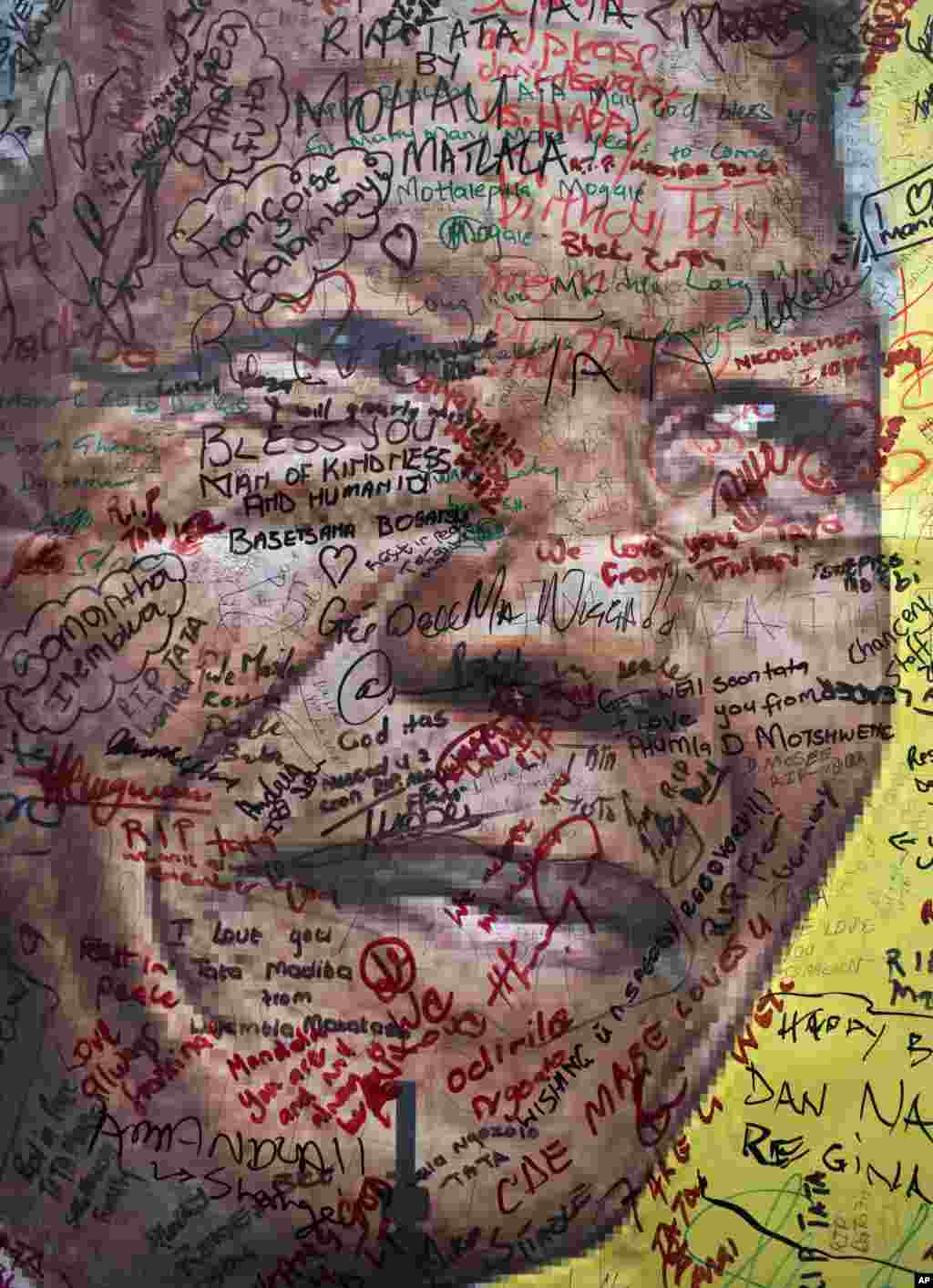 A poster of Nelson Mandela on which well-wishers have written their messages of condolence and support, in the street outside his old house in Soweto, Johannesburg, South Africa.