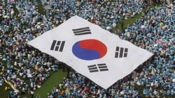 FILE - Orang-orang membawa bendera nasional Korea Selatan saat unjuk rasa anti-Korea Utara di Seoul, 6 Juni 2011. Pusat Penanggulangan Terorisme Nasional Korea Selatan menaikkan tingkat pengawasan teror negara itu ke status 'waspada', 2 Mei 2024.