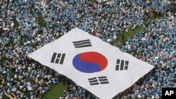 People carry a large scale South Korean national flag during an anti-North Korea rally marking Memorial Day in Seoul, June 6, 2011
